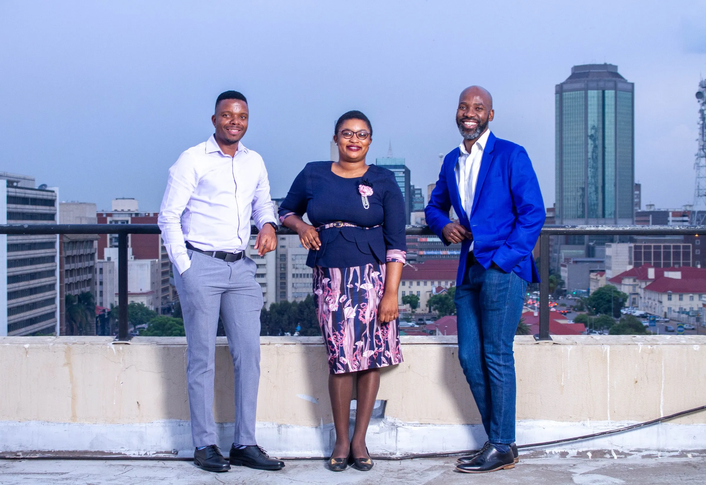 Evans Chinembiri with colleagues on a rooftop at dusk, city skyline behind